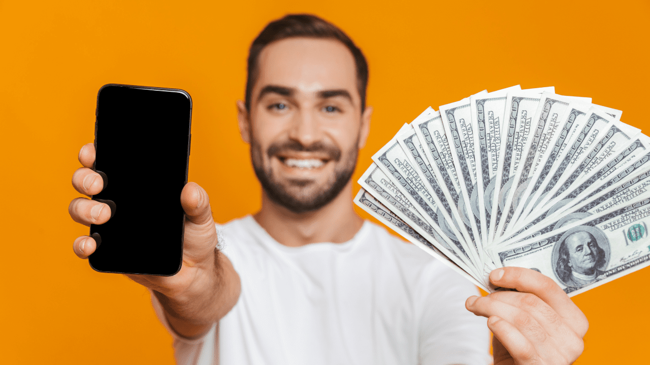 man holds phone and cash to demonstrate apps that pay real money in 2024