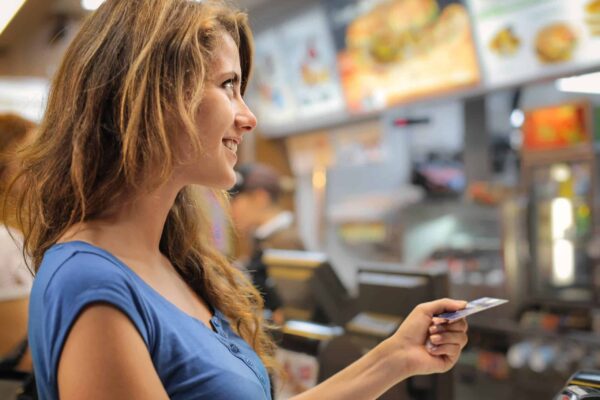 woman swipes her card at a restaurant because some fast food places take EBT