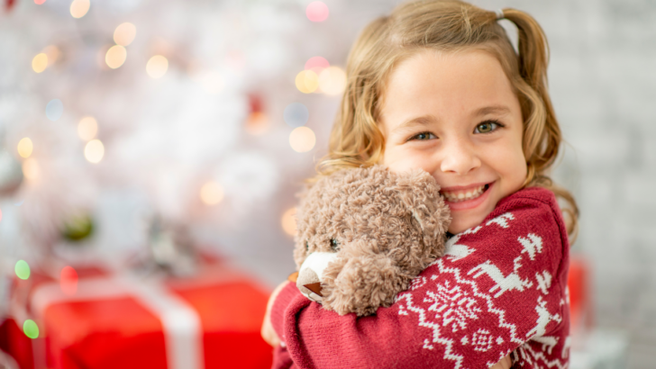 girl hugs teddy bear she got from free Christmas help in Arkansas