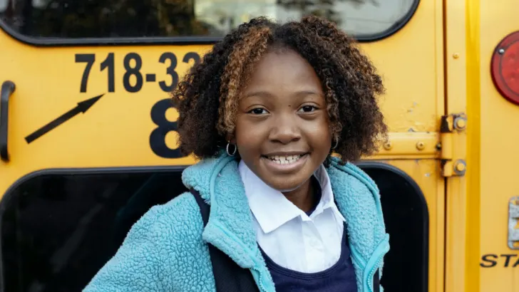 child stands behind school bus with free school supplies in Washington DC