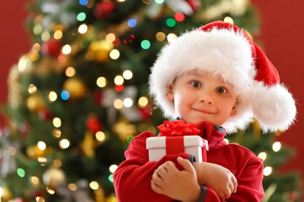 low income child holds free Christmas gifts after parents find Christmas help in Utah