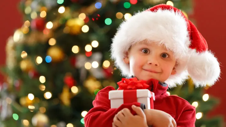 low income child holds free Christmas gifts after parents find Christmas help in Utah