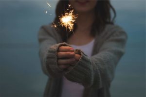 woman with sparkler happy because she saved money on these top new year's resolutions