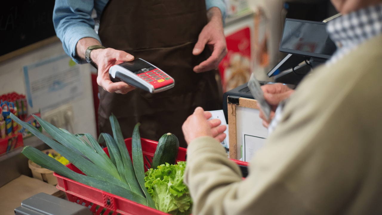 person pays for groceries and wonders how to save money on groceries