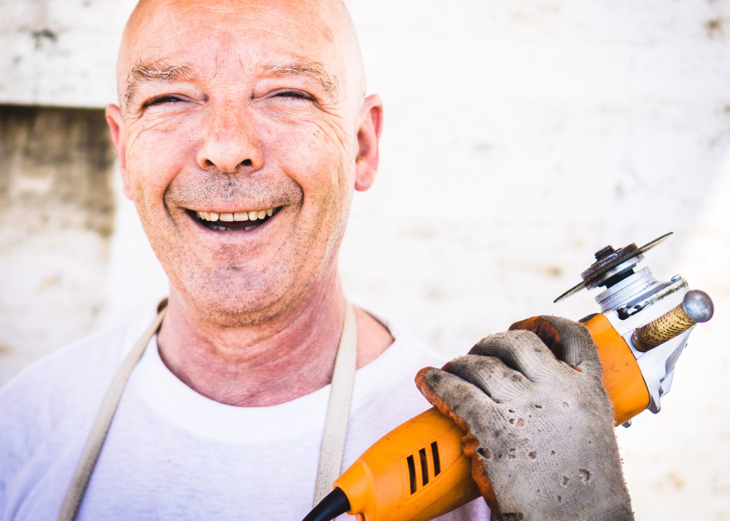 Man holding power tool and smiling. Start of third heading: how to get a job when you get out of prison