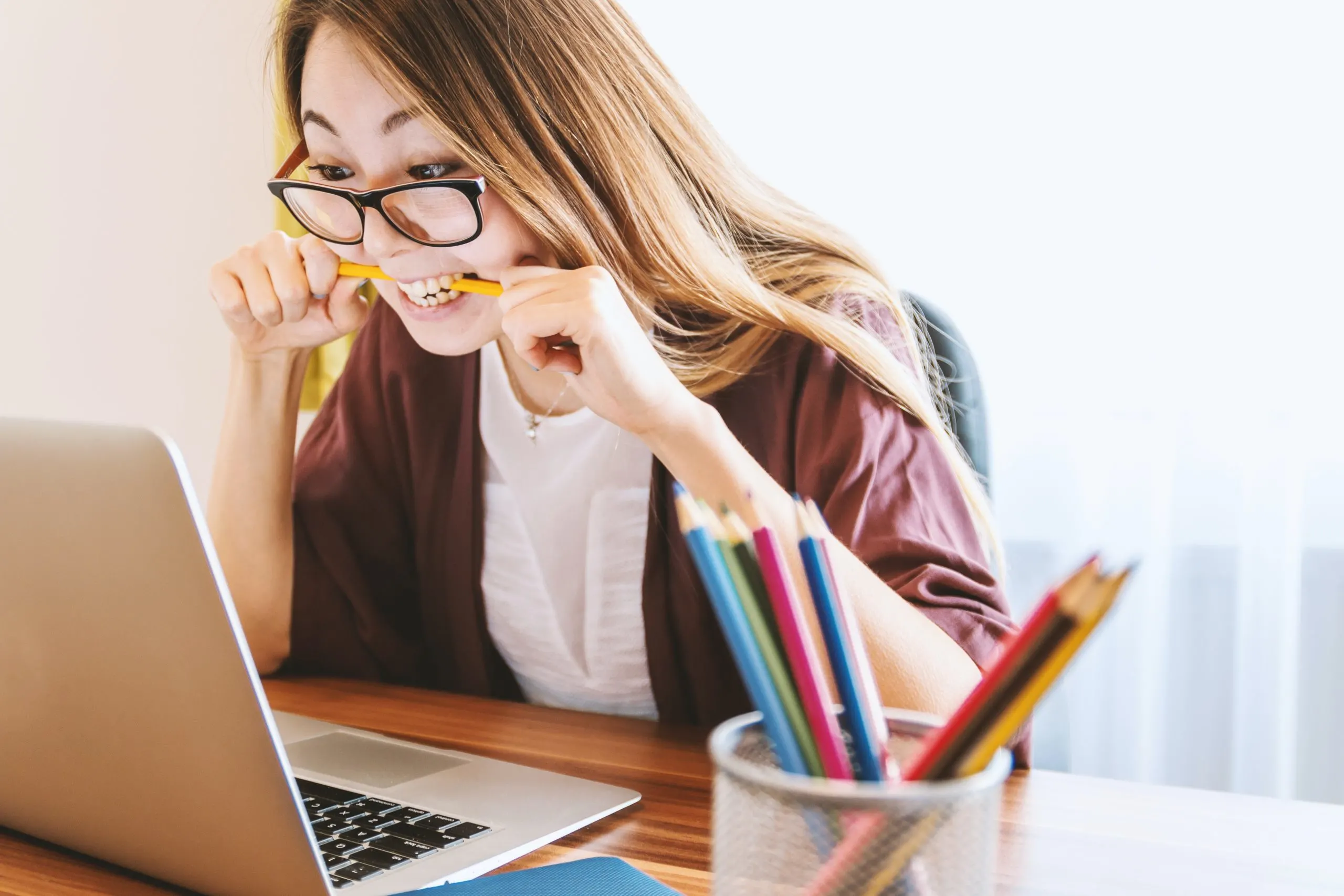 Woman anxiously biting a pencil while looking over her student loan statement in free debt advice article. 