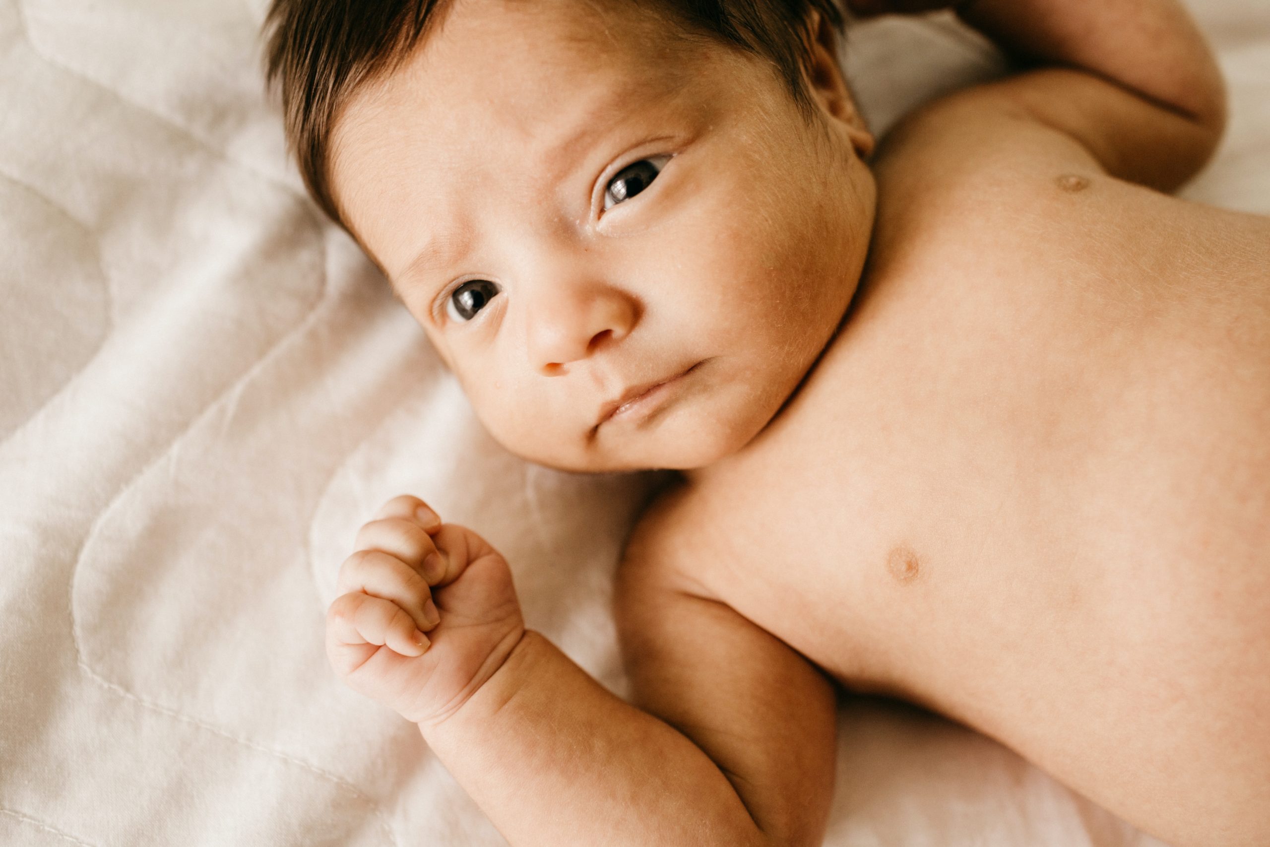 A baby of about three months old lying on a white blanket to demonstrate that infants are eligible for head start.