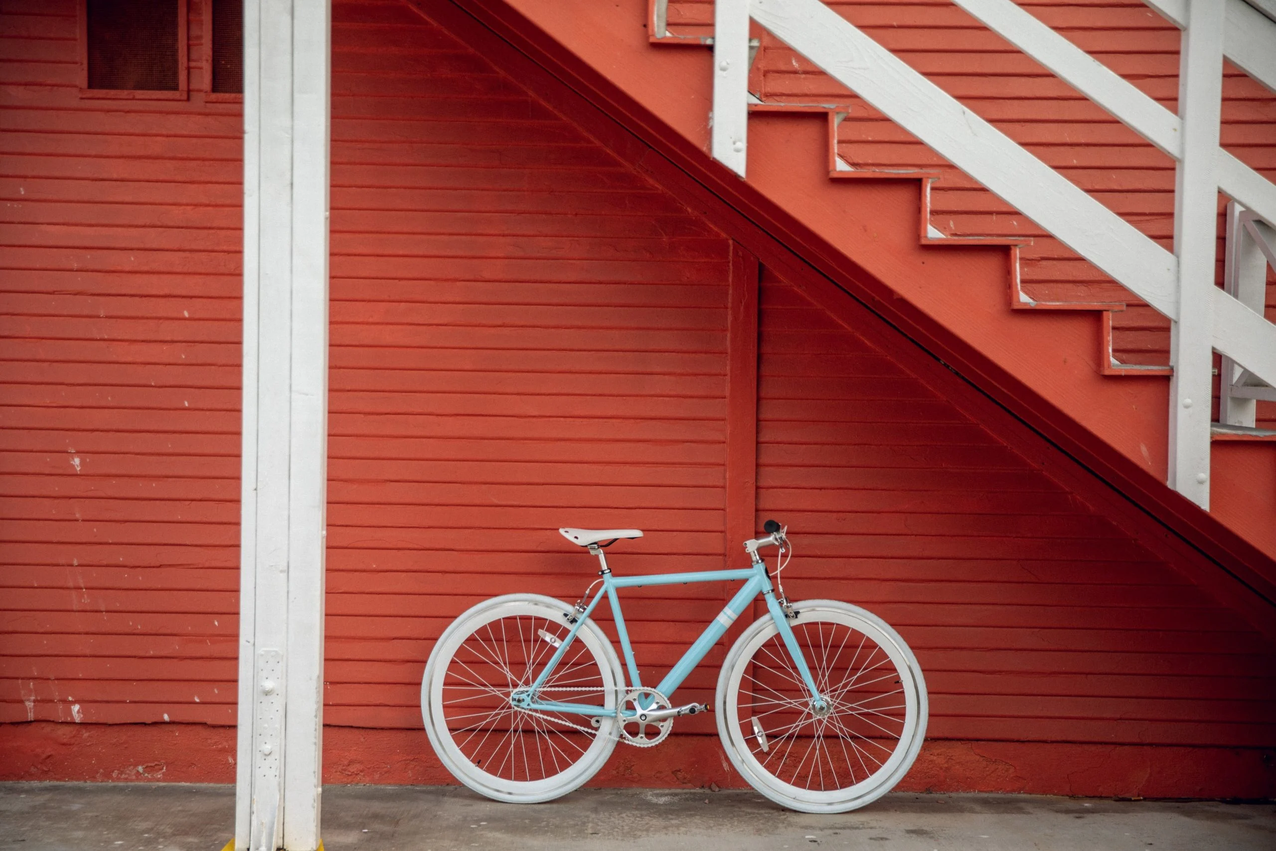 Blue and white bicycle leaning against a red painted wall in article on how to get free money.