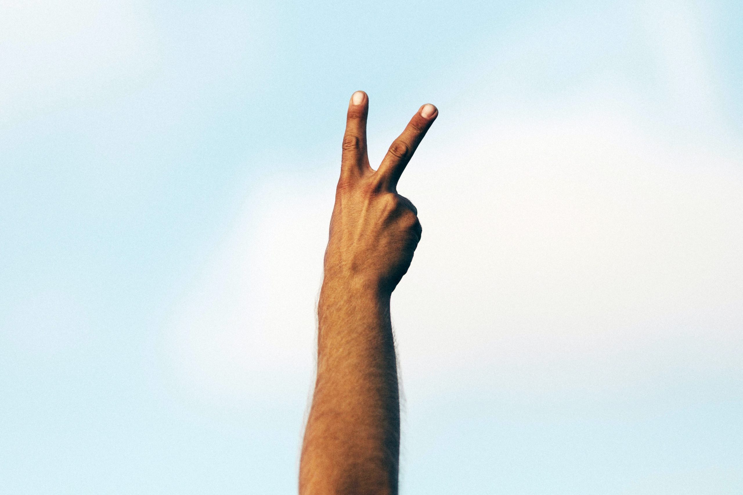 Person raising up their hand with a peace sign in article about how to get free housing