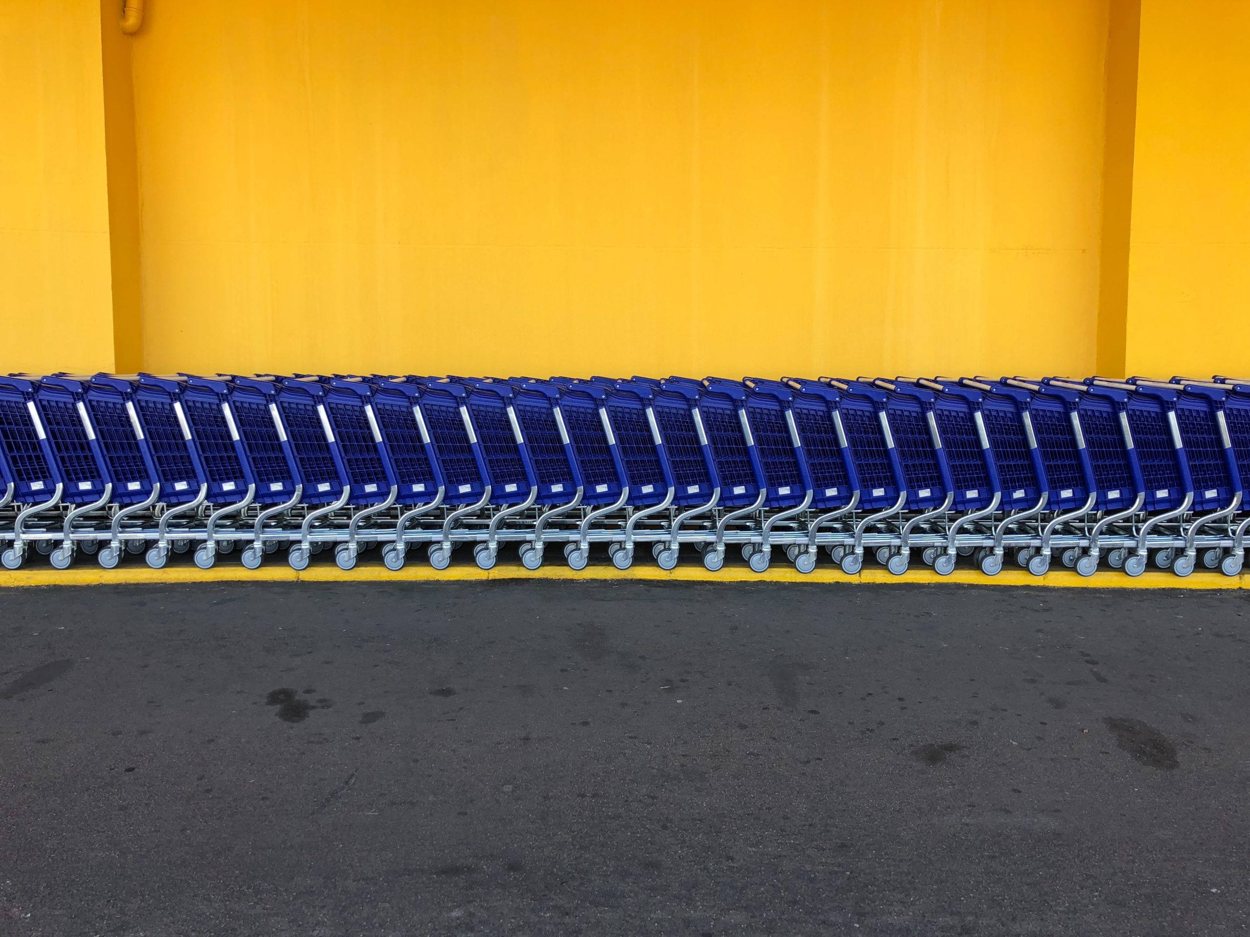 row of blue shopping carts against yellow wall in article on can you spend cash ebt online?