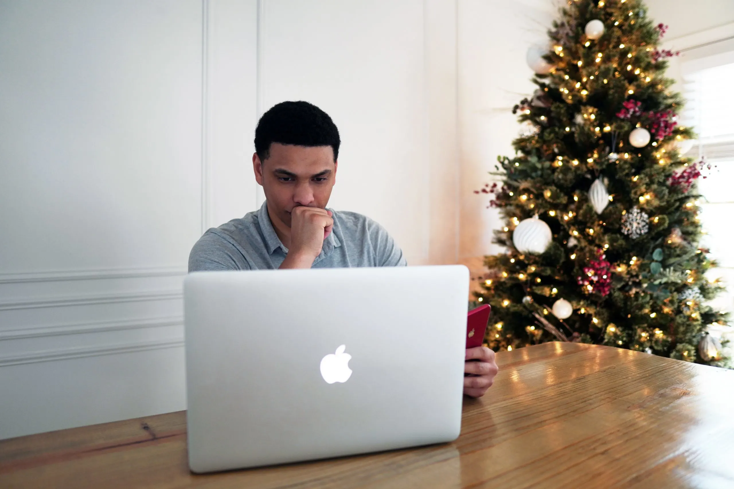 photo of man at laptop in front of a Christmas tree in article about i need help but i don't know what to do