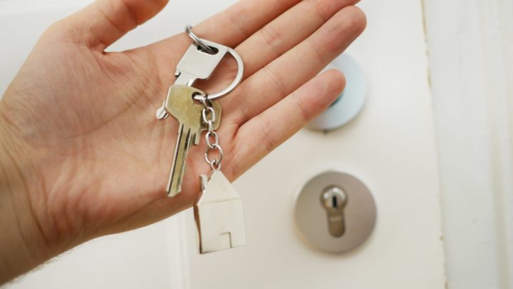 hand holding a set of keys on a keychain shaped like a house in article about can a landlord charge more than the security deposit