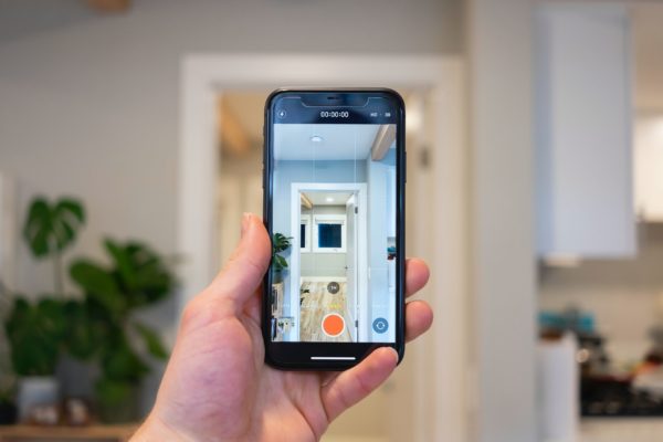photo of a hand holding a smartphone taking a photo of an apartment in article on how do security deposits work