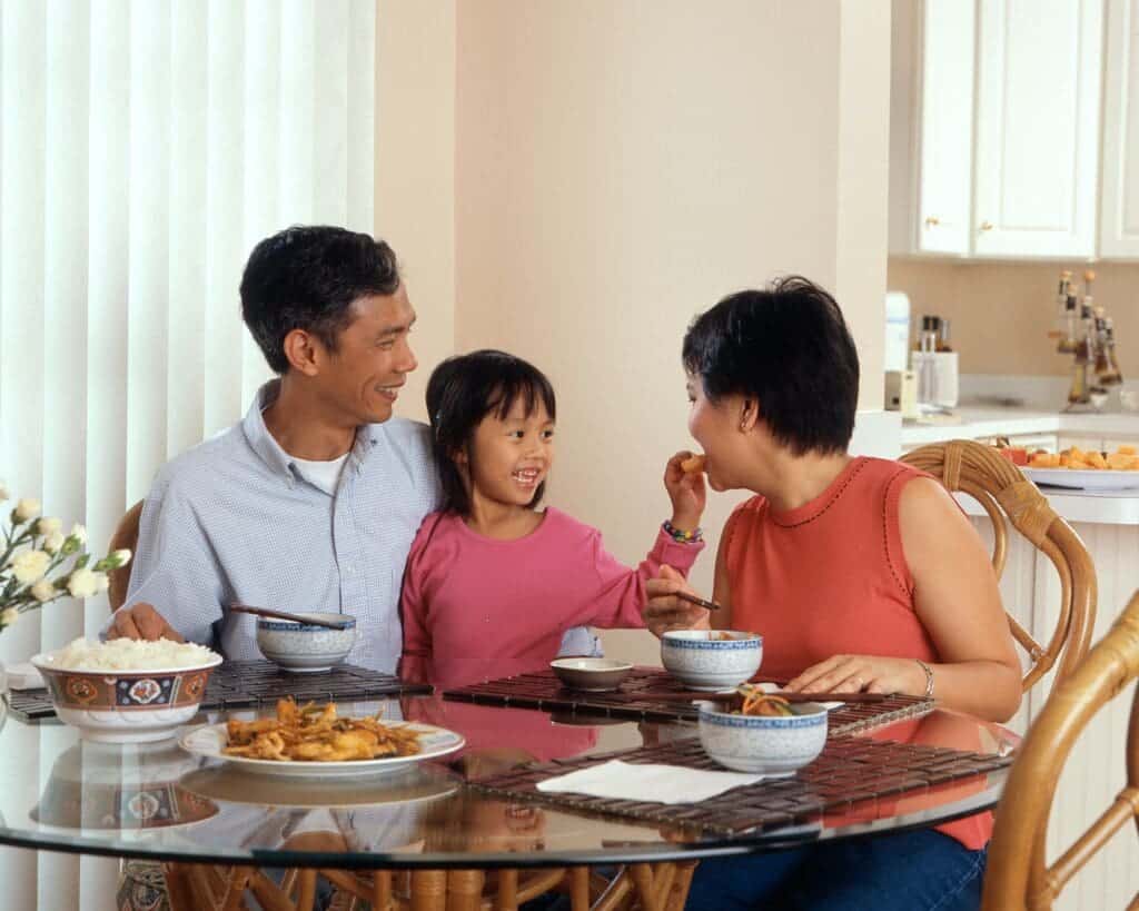 father, mother, and daughter sitting at a breakfast table at home in article about arkansas transitional employment assistance