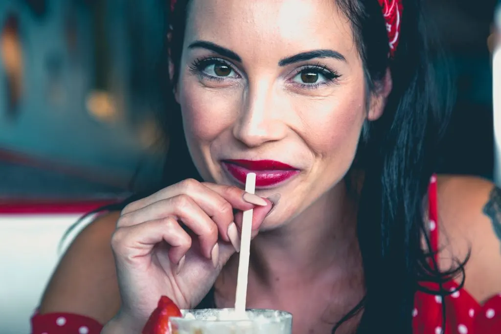 woman wearing red lipstick and drinking a milkshake in article on does burger king take ebt