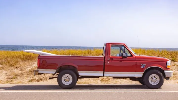 red truck driving past beach with a surfboard in the bed in article on California's consumer assistance program