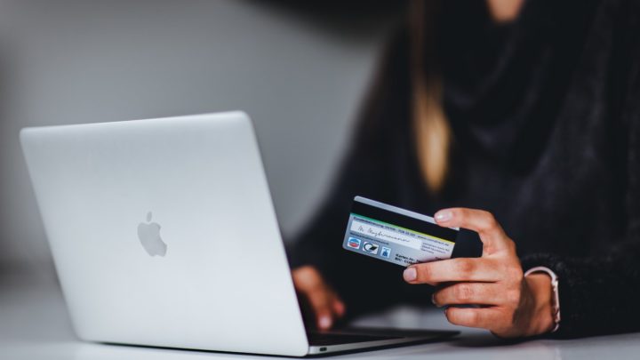 By Unsplash user Pickawood. A person uses their Mac laptop with a credit card in hand.