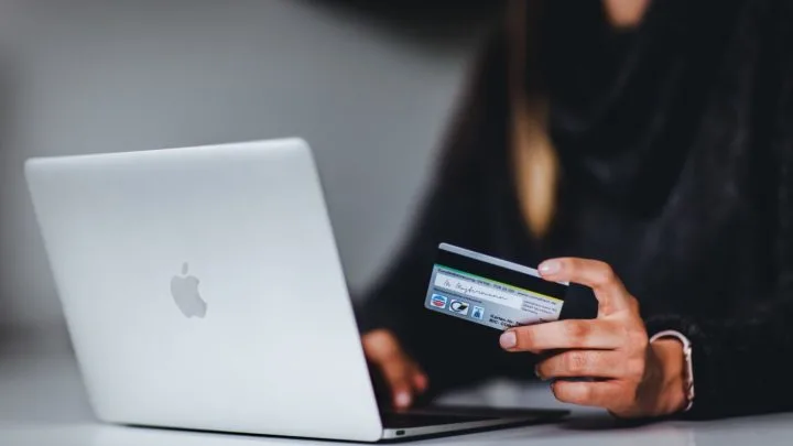 By Unsplash user Pickawood. A person uses their Mac laptop with a credit card in hand.