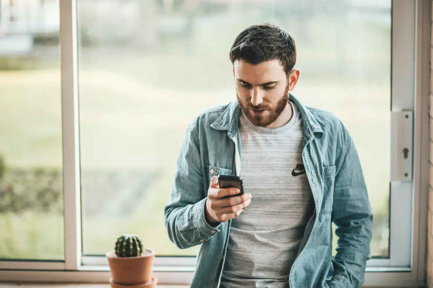 By Unsplash user Thom Holmes. A man looks at his phone held in his hand.