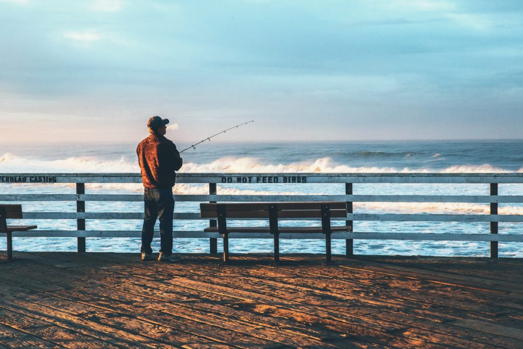 man fishing on a pier in article on California fishing license discounts