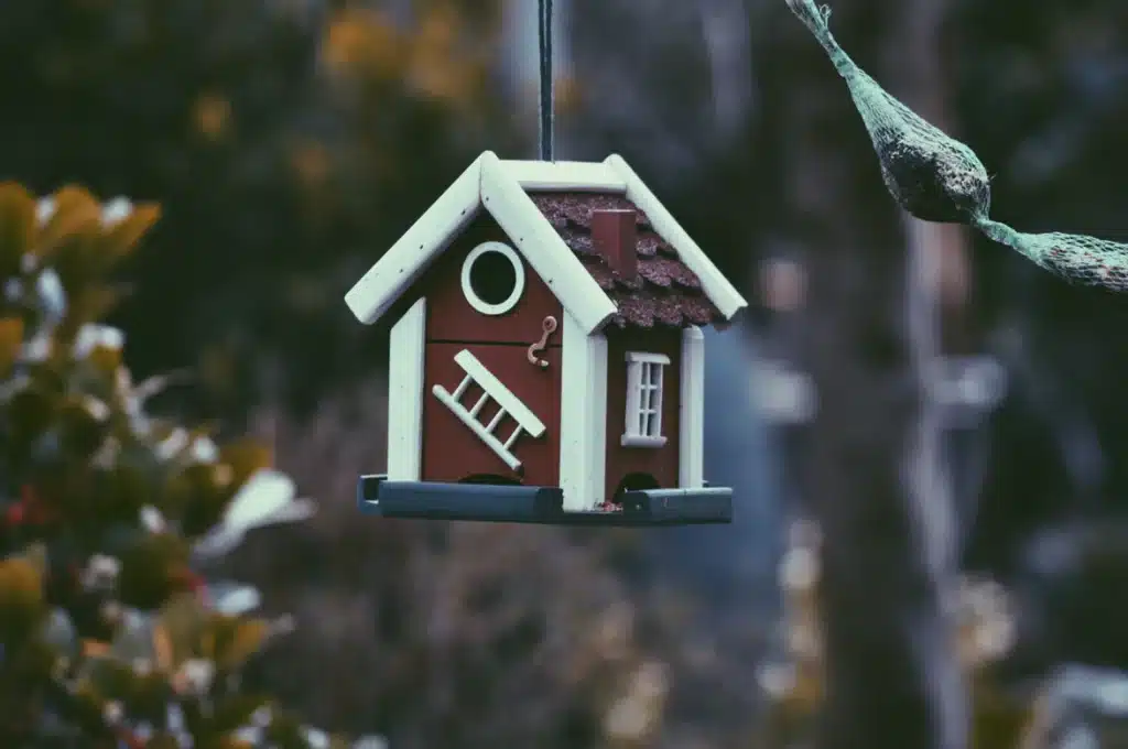 By Unsplash user Harmen Jelle van Mourik. A brown house ornament hangs outside in the forest.