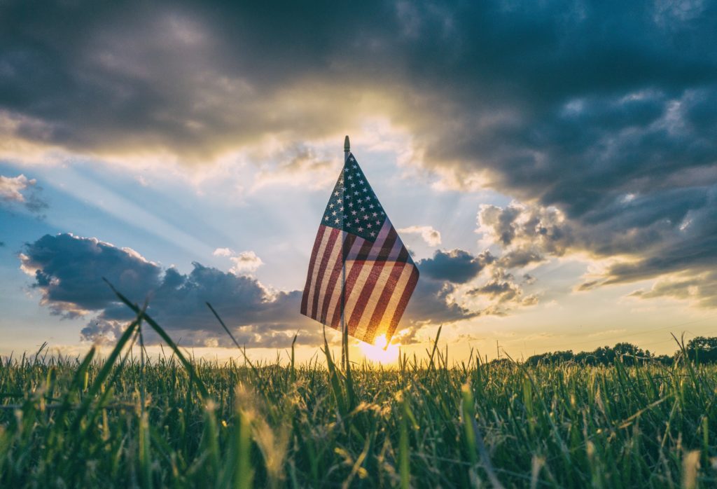 Image of American flag in a field of grass in article on Alaska State veterans benefits