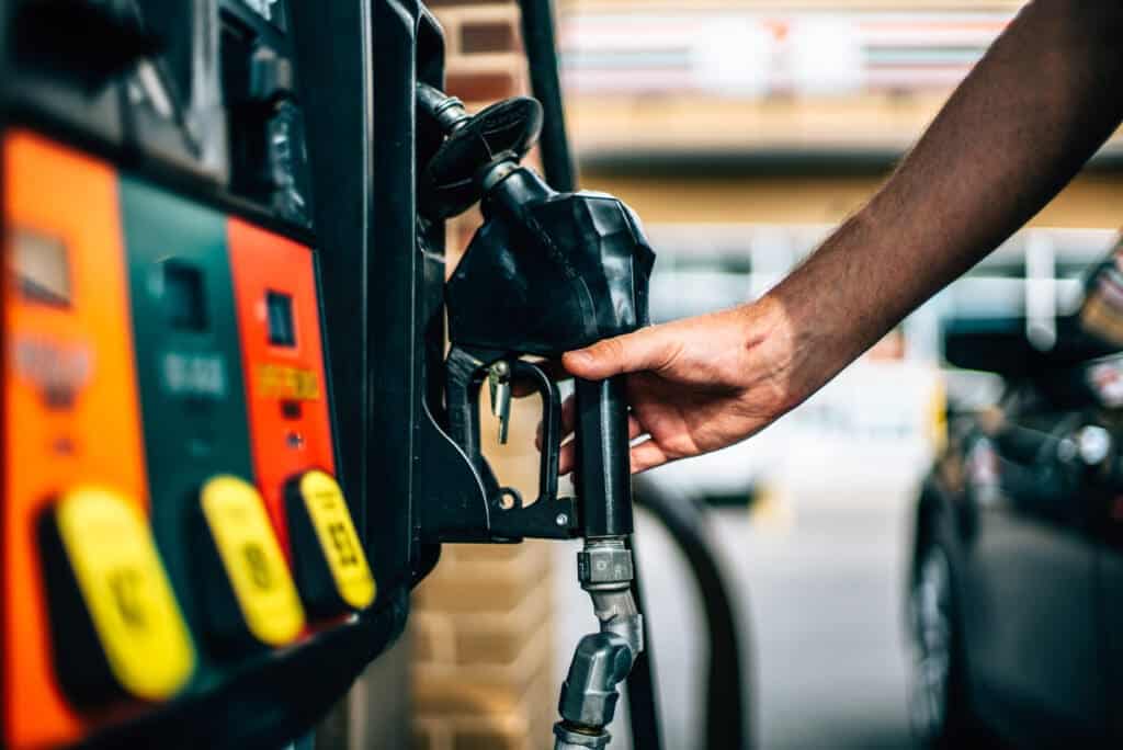 man reaches for gas pump after paying with free gas vouchers near him