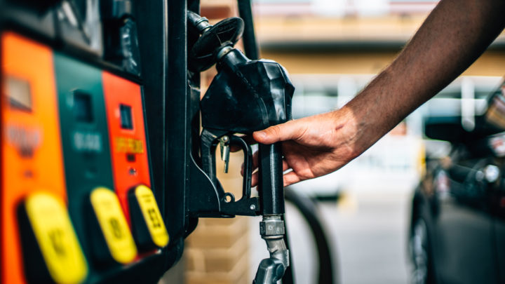 man reaches for gas pump after paying with free gas vouchers near him