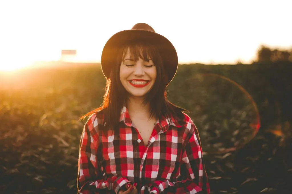 woman in hat and plaid shirt standing in field in article on how to build credit with low income
