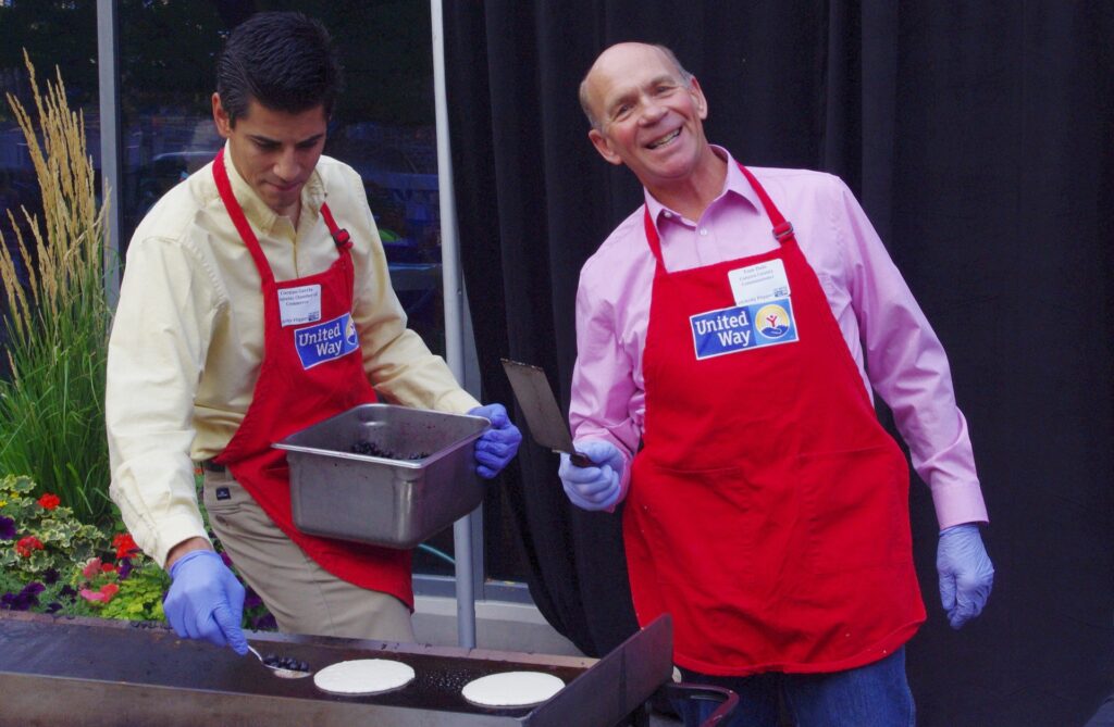 Two United Way volunteers making blueberry pancakes.