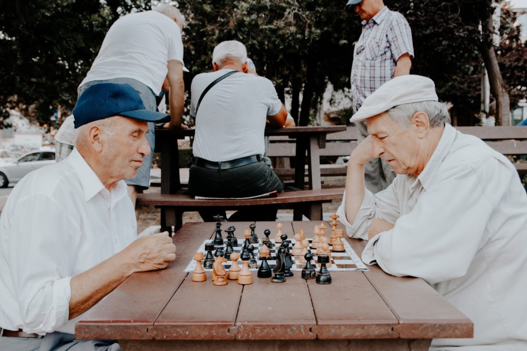 Two older men playing chess in a park in article on is social security taxable