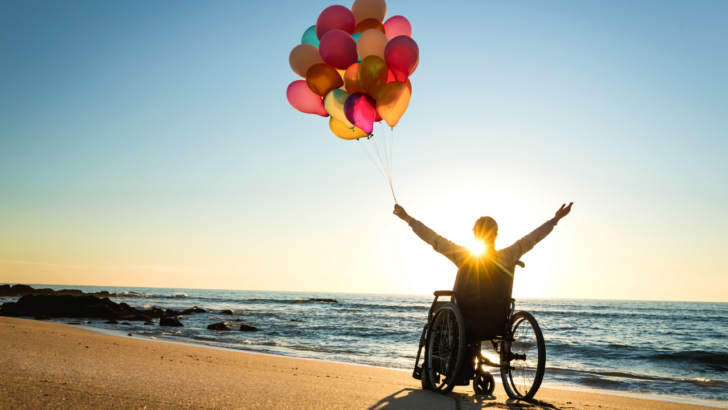 person in wheelchair celebrates beach trip paid for by a wish-granting organization like make a wish for adults