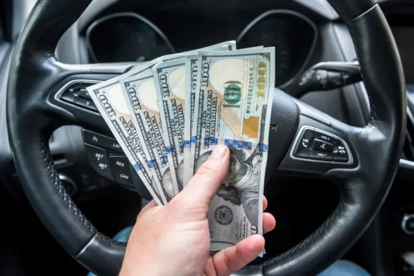 woman holds cash from charities that help with car payments