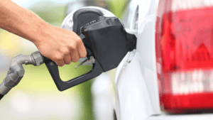 hand holds gas nozzle in white vehicle after receiving free gas cards for cancer patients