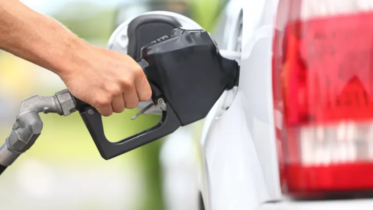 hand holds gas nozzle in white vehicle after receiving free gas cards for cancer patients