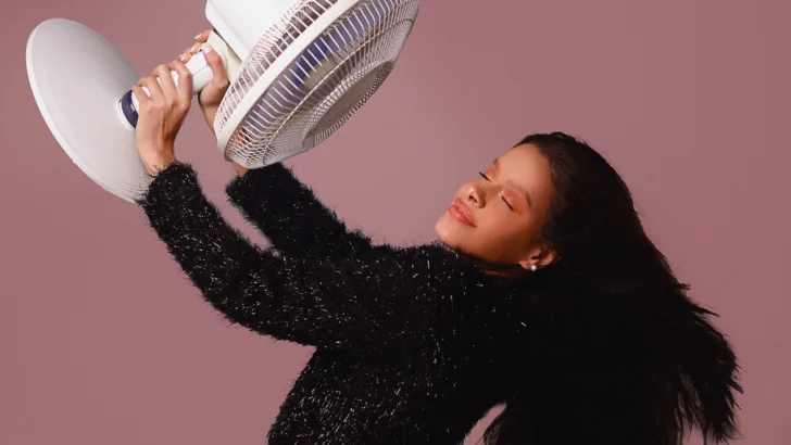 woman holds a fan to cool down as she looks for places to escape the heat near me