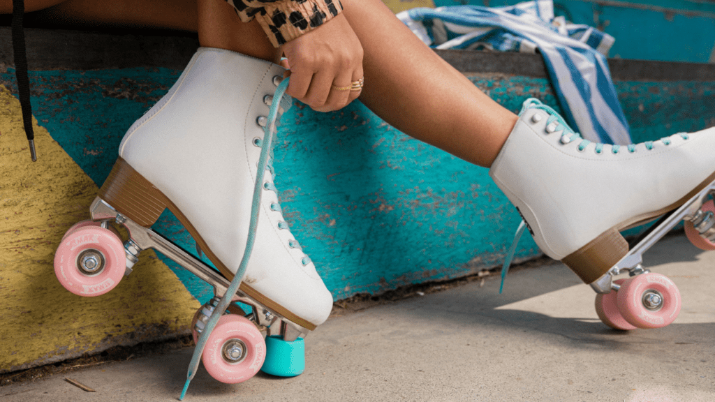 person laces white skates with pink wheels at kids skate free program