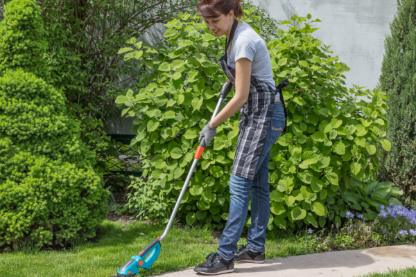 woman with edge trimmer provides free lawn care for seniors
