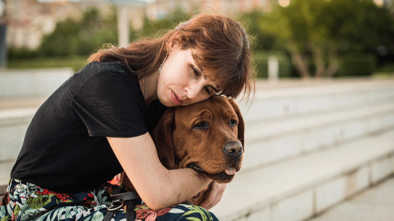 woman hugs dog in park after receiving a free psychiatric service dog for anxiety