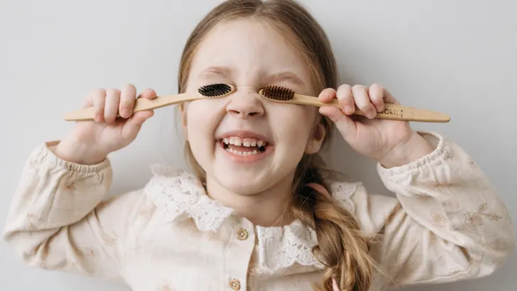 girl holds free toothbrushes over her eyes