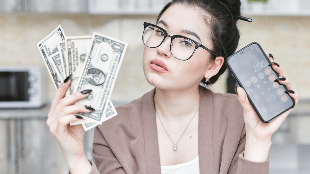 woman holds up cash and a calculator to show her profits from lazy ways to make money online in 2025